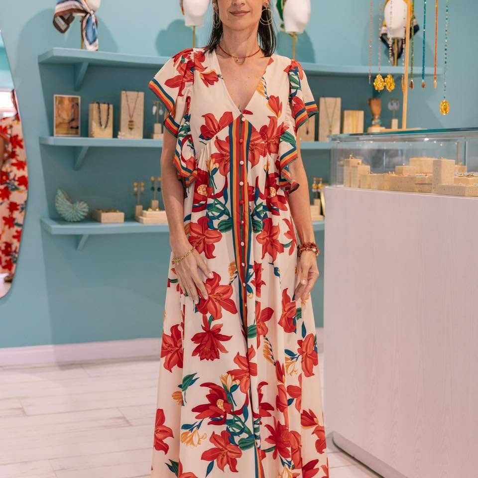 Robe longue fleurie portée dans la boutique Aquamarine, étagères de bijoux en arrière-plan